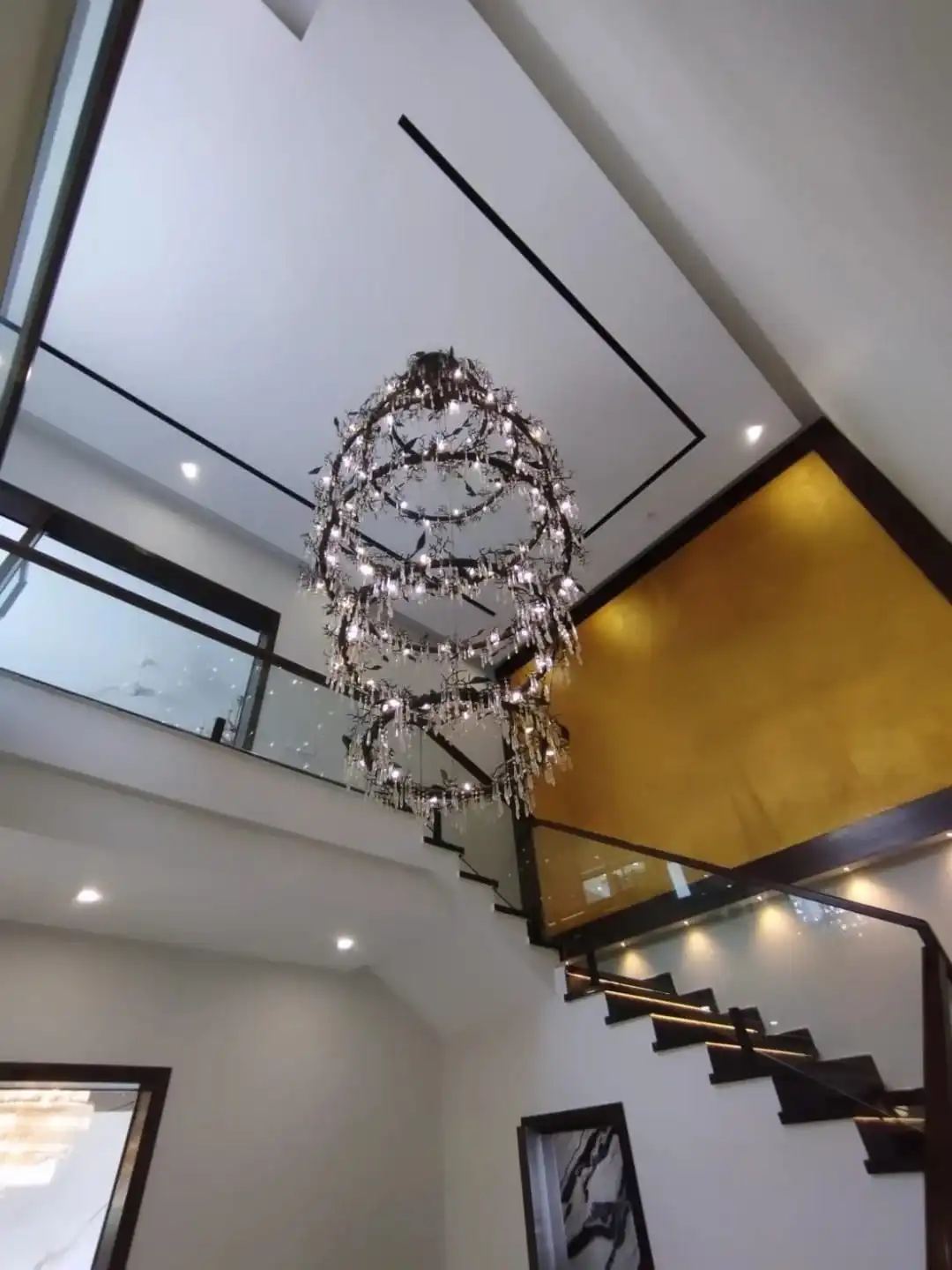 Grand Double-Height Staircase & Foyer – 1 Kanal Signature Residence Lake City M3 Double height staircase with glass railing sculptural chandelier and gold accent wall in 1 Kanal house Lake City