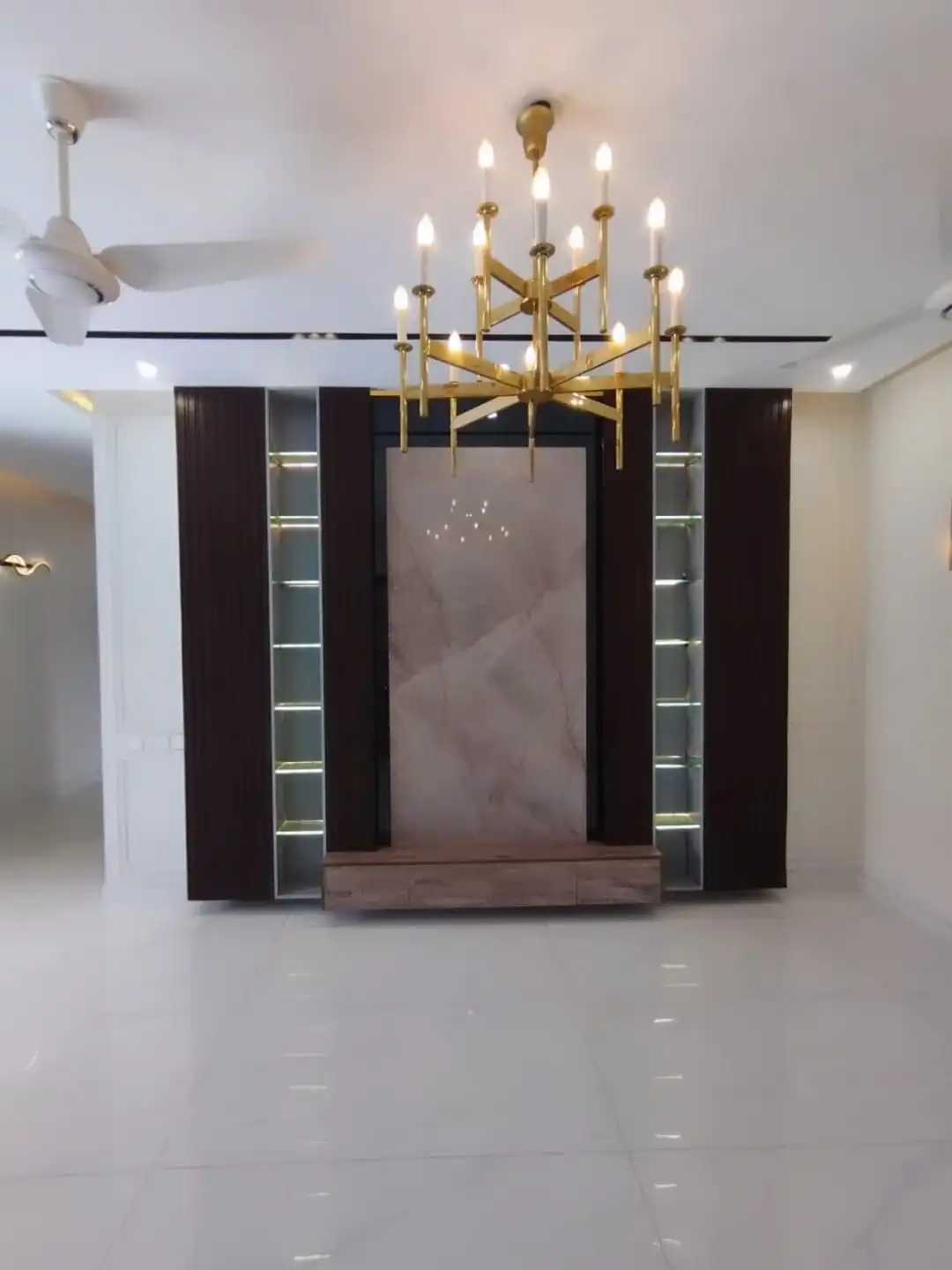 Luxury TV Lounge with Custom Entertainment Unit – Lake City M3 Lahore Family TV lounge with dark wood entertainment unit marble panel and gold chandelier in 1 Kanal house Lahore