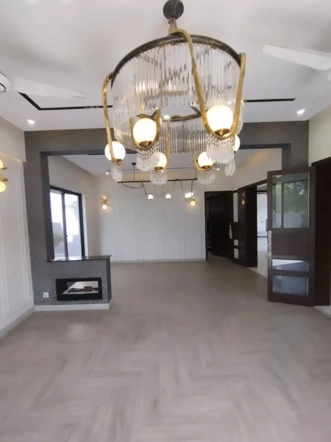 Grand Drawing Room with Fireplace – 1 Kanal Luxury House Lake City M3 Lahore Spacious drawing room with crystal chandelier fireplace and open plan layout in 1 Kanal house Lake City M3