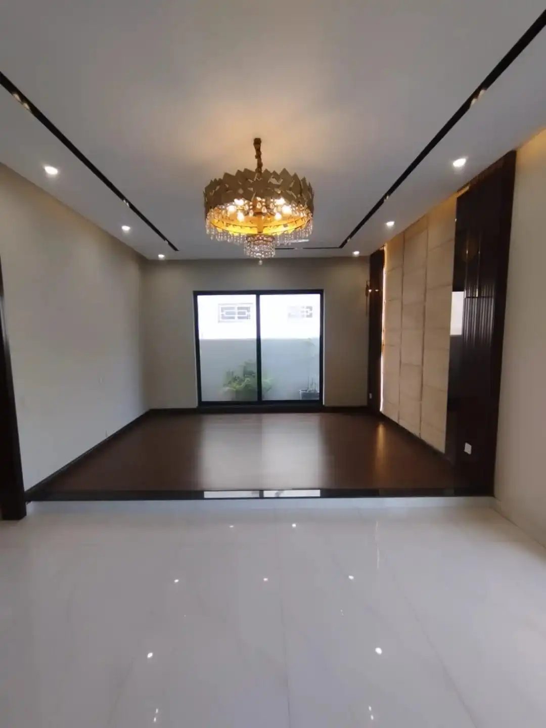 Elegant Master Bedroom with Premium Finishes – Lake City M3 Lahore Luxury bedroom with gold chandelier dark wood flooring and padded wall panel in Lake City M3 Lahore