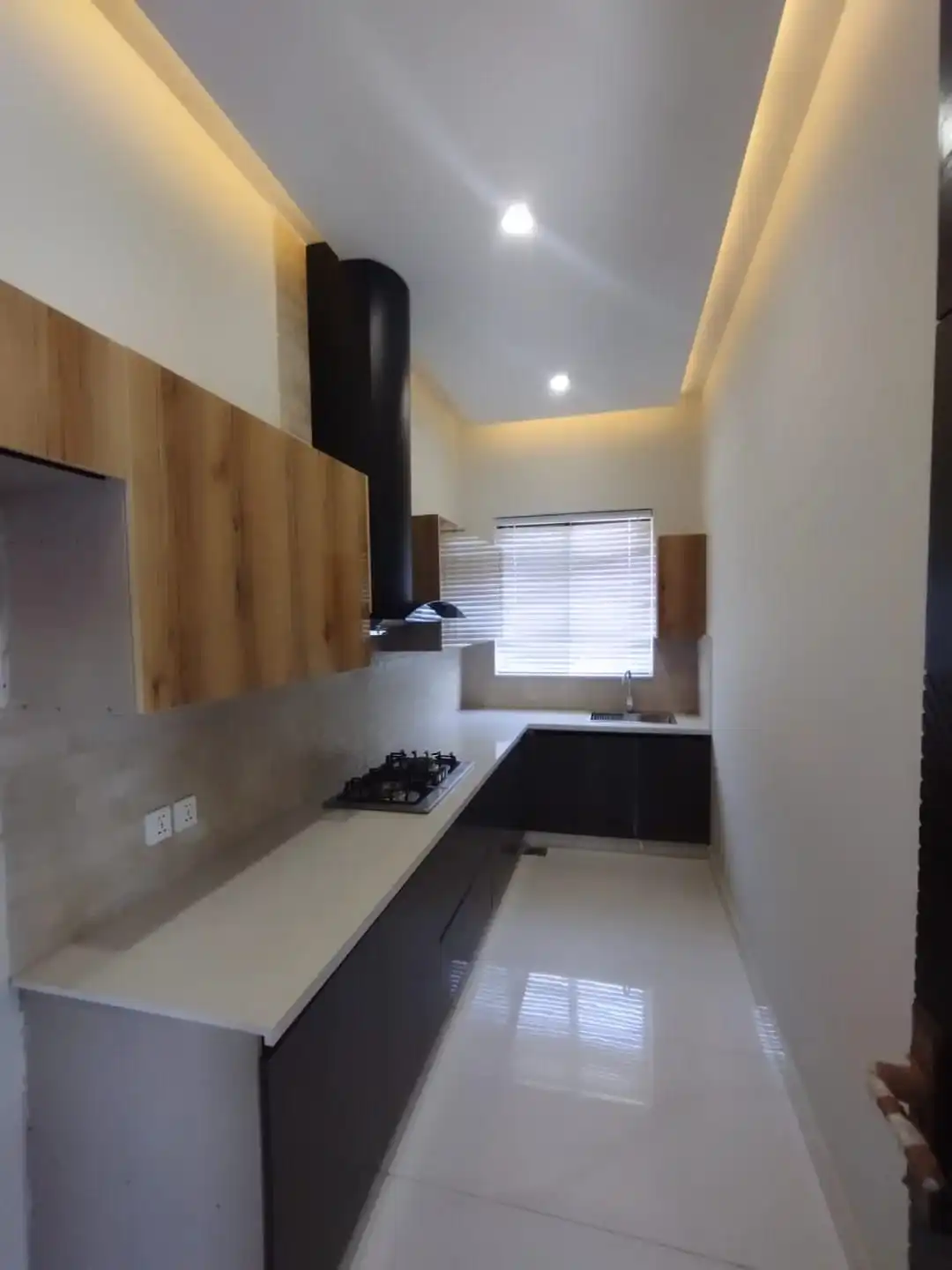Stylish Modular Kitchen – 1 Kanal Luxury House for Sale Lake City M3 Modern modular kitchen with wooden cabinets and black chimney hood in 1 Kanal house Lake City Lahore