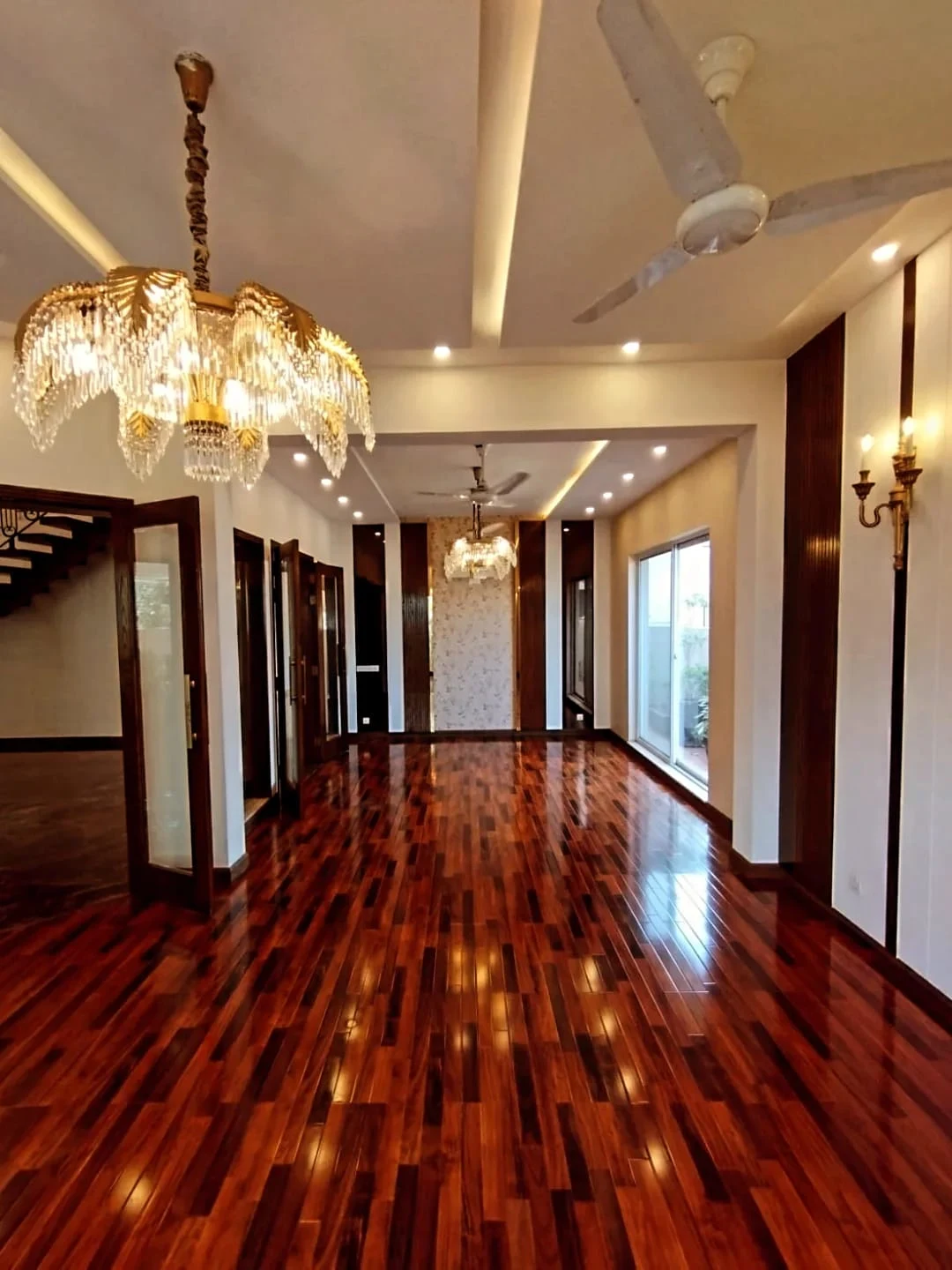 Luxury Grand Hall with Crystal Chandeliers – 1 Kanal House Lake City M2 Grand hallway with high gloss wooden flooring, crystal chandeliers and dark wood wall panels in luxury 1 Kanal house Lake City Lahore