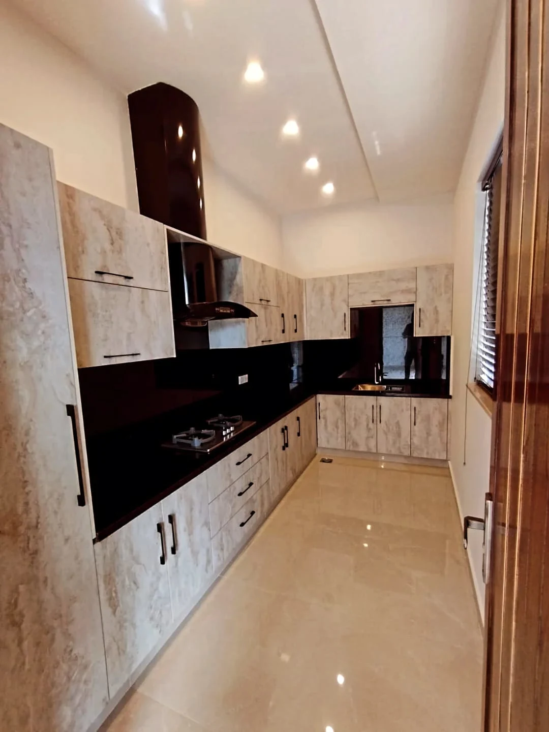 Designer Modular Kitchen – 1 Kanal House for Sale Lake City M2 Lahore Designer modular kitchen with marble finish cabinets, black granite countertop and chimney hood in 1 Kanal house Lake City Lahore
