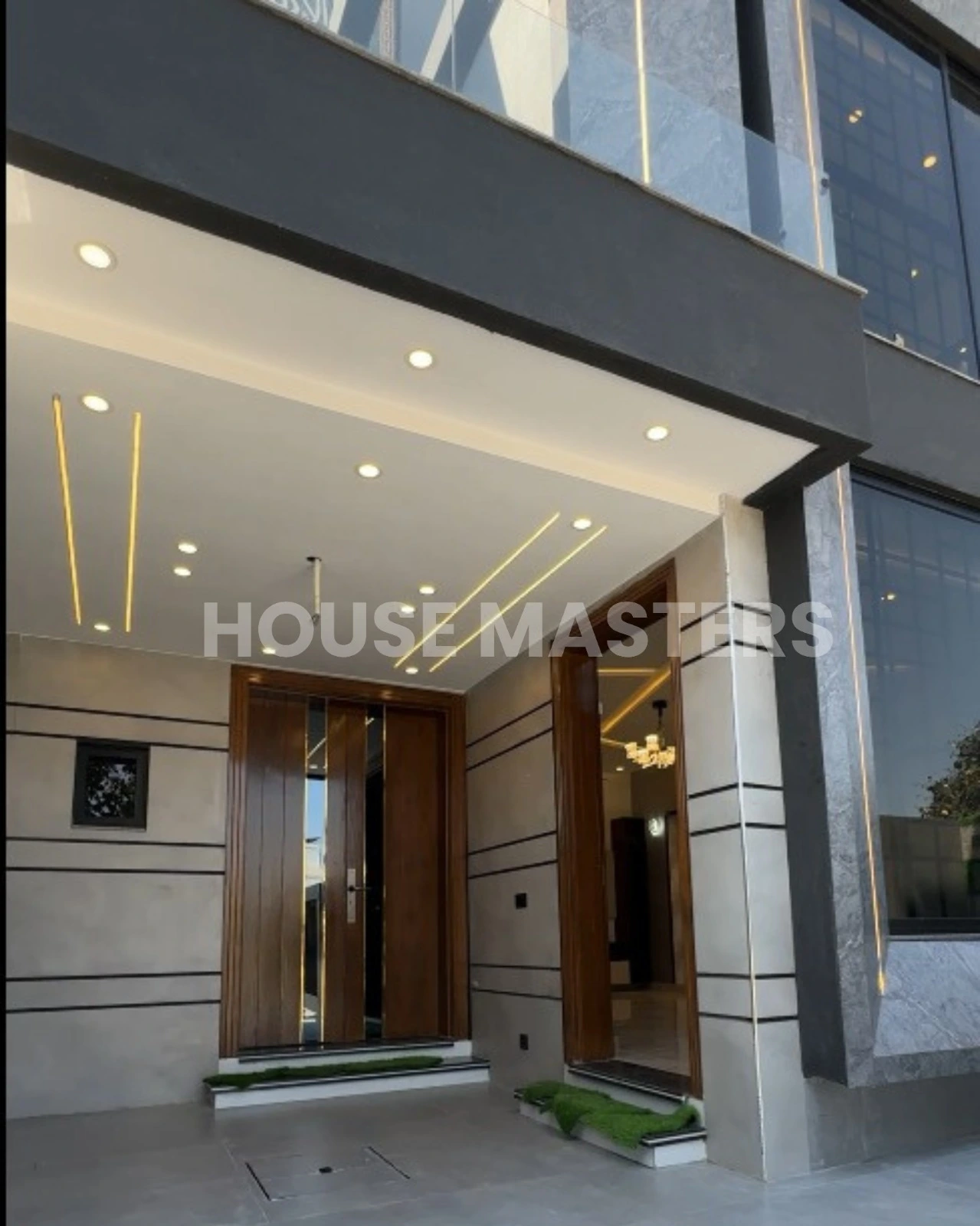 Elegant main entrance with modern lighting, wooden doors, and stylish facade in a luxury 5 Marla house in Bahria Orchard, Lahore.