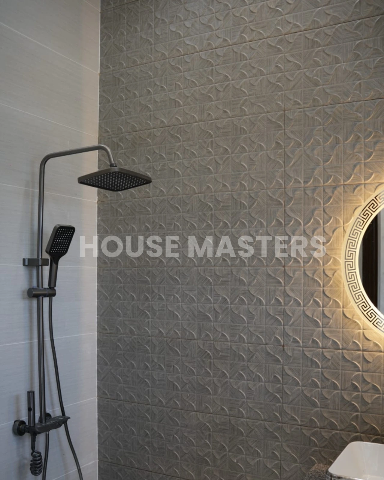 Stylish bathroom with leaf-pattern accent wall, black countertop, and illuminated round mirror in 5 Marla luxury home, Bahria Orchard.