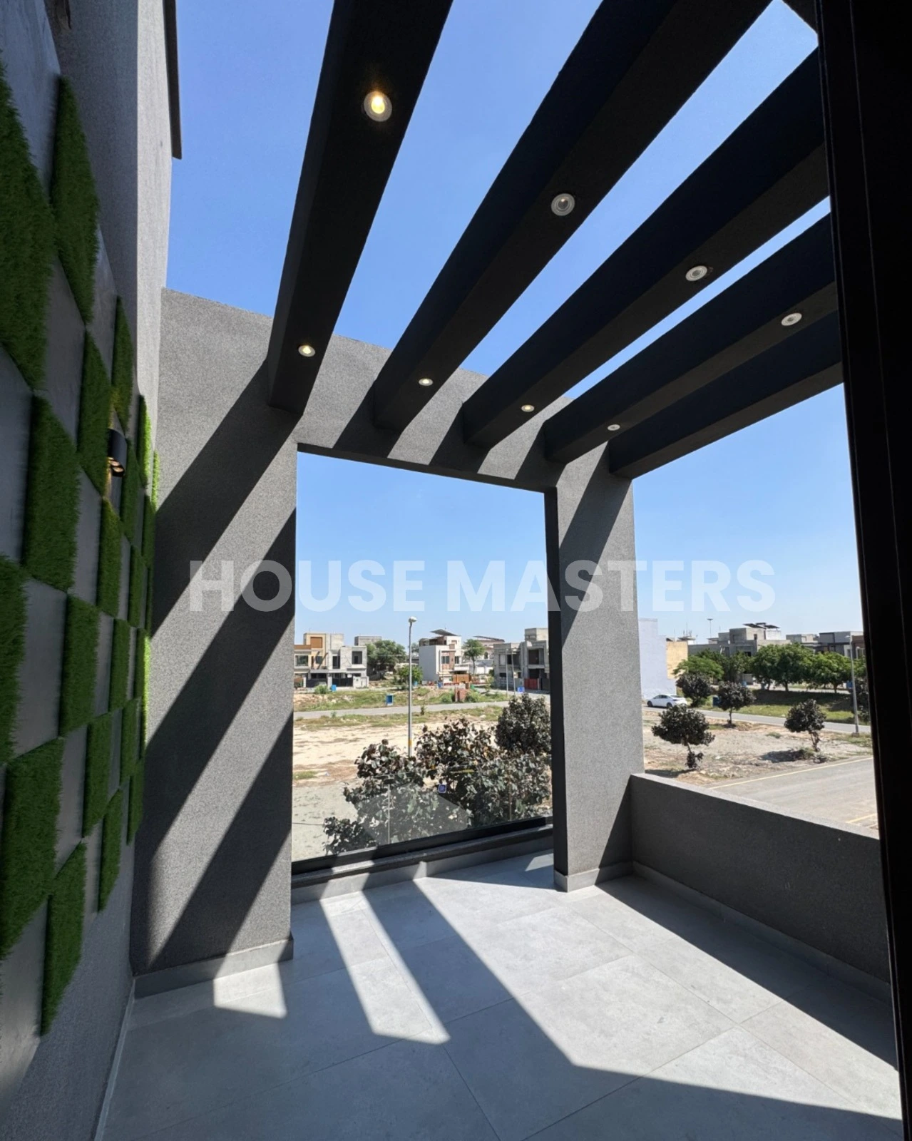 Modern balcony with black beams, grey flooring, and partial outdoor view in 5 Marla premium home, Bahria Orchard.
