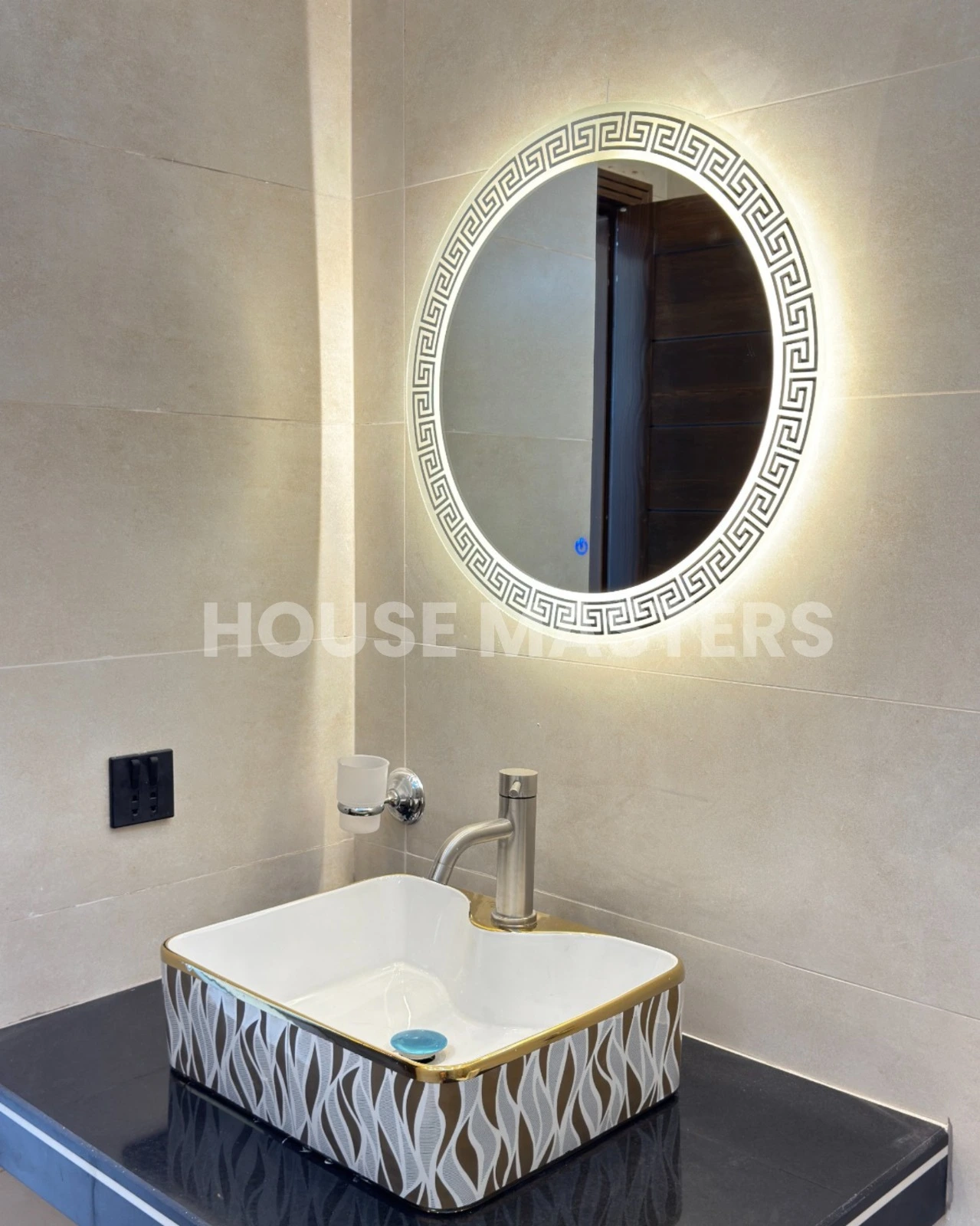 Stylish bathroom with leaf-pattern accent wall, black countertop, and illuminated round mirror in 5 Marla luxury home, Bahria Orchard.