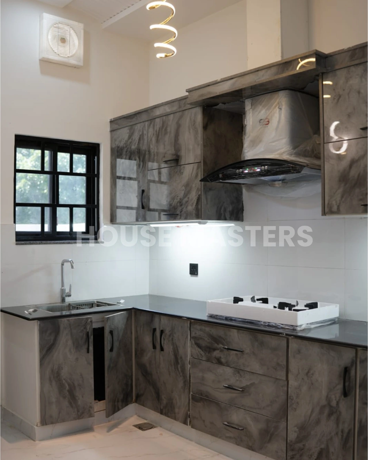 High-end kitchen with dark marble cabinets, black countertops, and modern appliances in 5 Marla luxury home, Bahria Orchard.