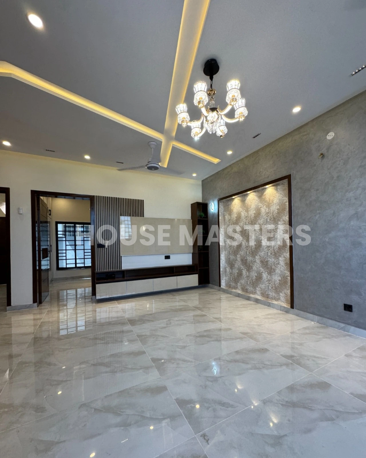 Spacious living room with modern chandelier, luxurious flooring, and contemporary wall design in a premium 5 Marla house in Bahria Orchard, Lahore.