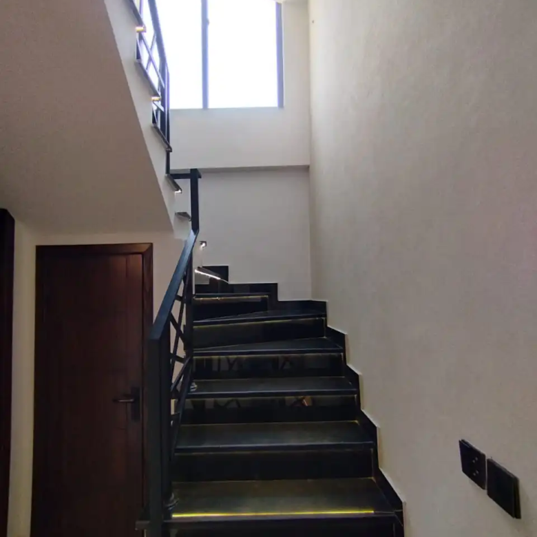 Black marble staircase design with tread lighting in 5 Marla house