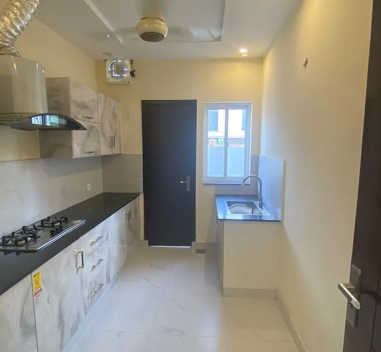 Modern bathroom with premium marble tiles, floating vanity, and round mirror in Lake City Lahore M8 house.