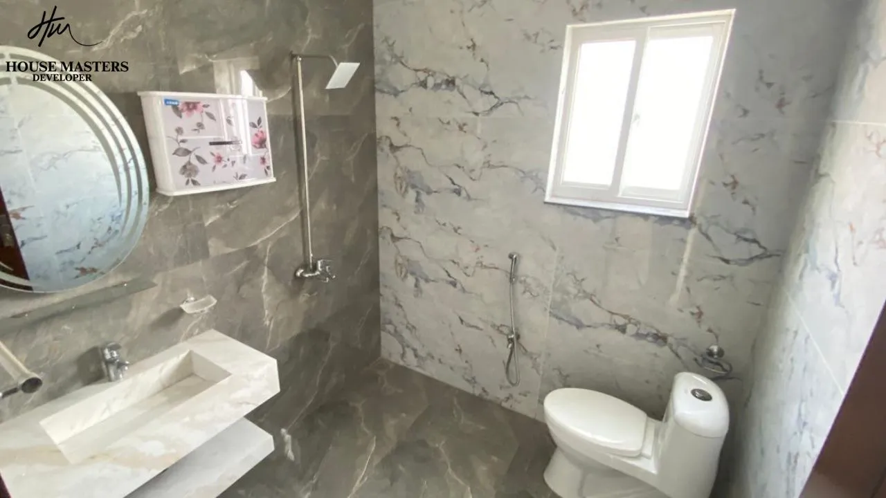 luxury bathroom interior 5 marla house Modern bathroom with premium marble tiles, floating vanity, and round mirror in Lake City Lahore M8 house.