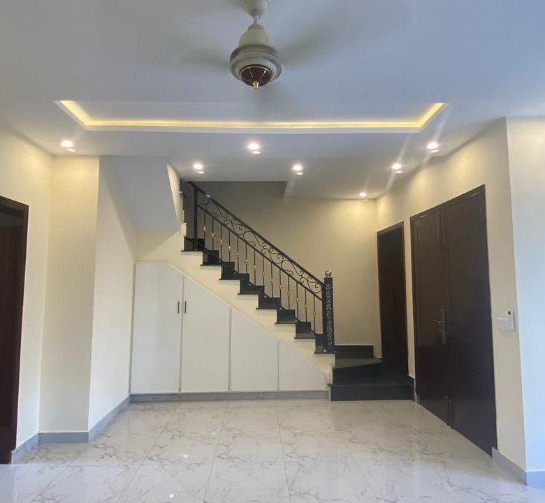 Modern lobby, tiled flooring, and under-stairs storage cabinets of a brand new 5 Marla home.